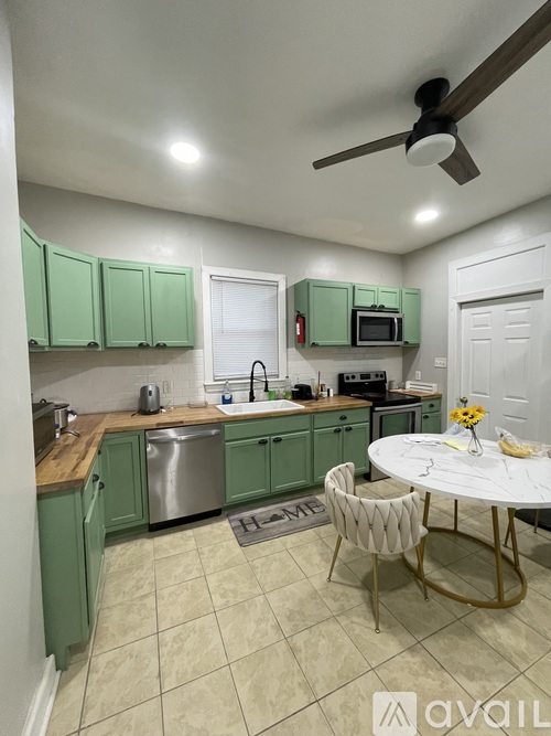A kitchen with green cabinets and a white ceiling fan.
