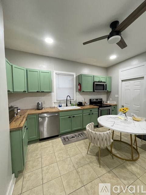 A kitchen with green cabinets and a white ceiling fan.
