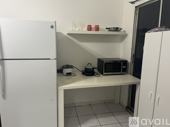 A small kitchen with a white fridge, microwave, and a small table.