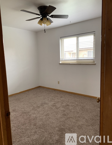 A room with a ceiling fan and a window with blinds.