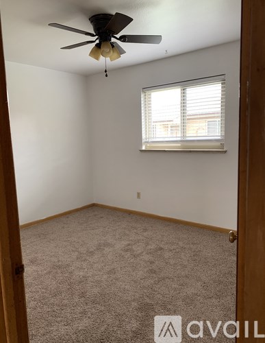 A room with a ceiling fan and a window with blinds.