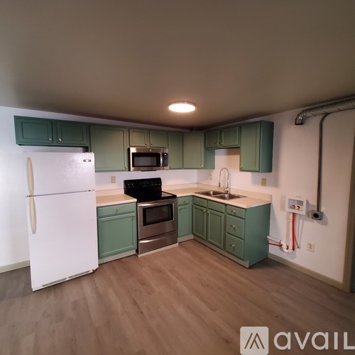 A kitchen with green cabinets and a white refrigerator.