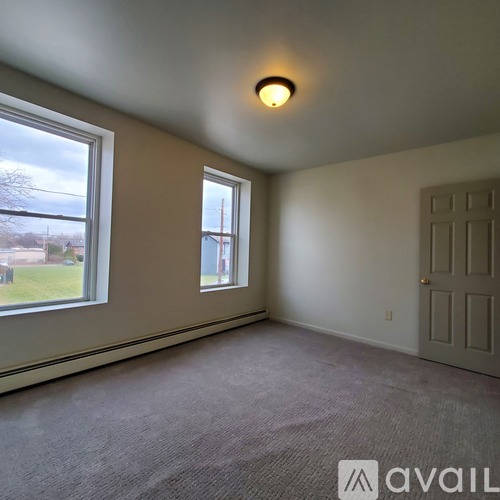 A room with a carpeted floor, a door, and a window.