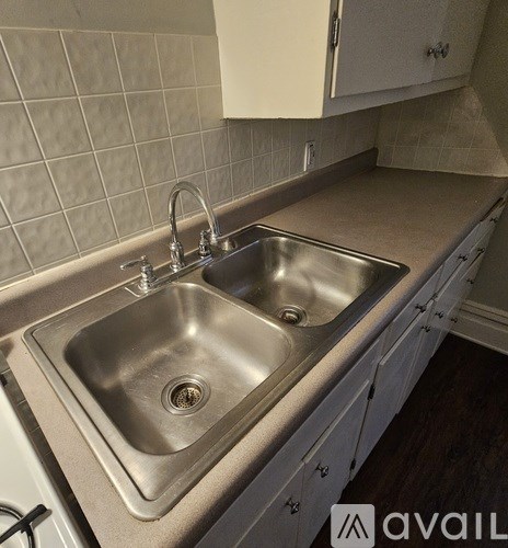 A kitchen with a double sink and white cabinets.