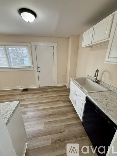 A kitchen with wooden floors and white cabinets.