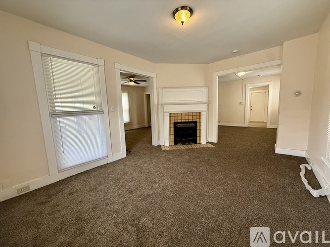 A living room with a fireplace and a window with blinds.
