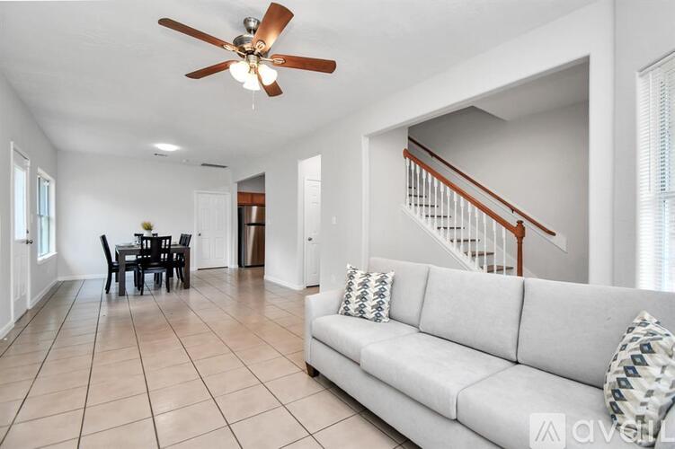 A living room with a couch, dining table, and a ceiling fan.