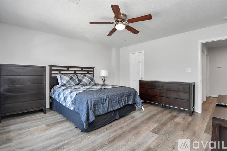 A bedroom with a bed, dresser, and ceiling fan.
