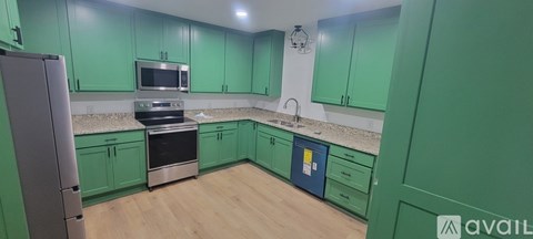 A kitchen with green cabinets and a stainless steel refrigerator.