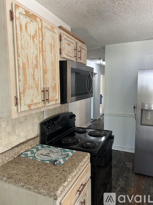 A kitchen with a black stove top oven and wooden cabinets.