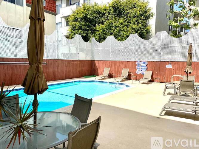 A pool area with chairs and an umbrella.