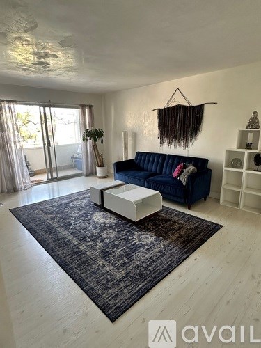 A living room with a blue couch and a rug.
