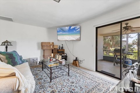 A living room with a flat screen TV mounted on the wall and a coffee table in the center.