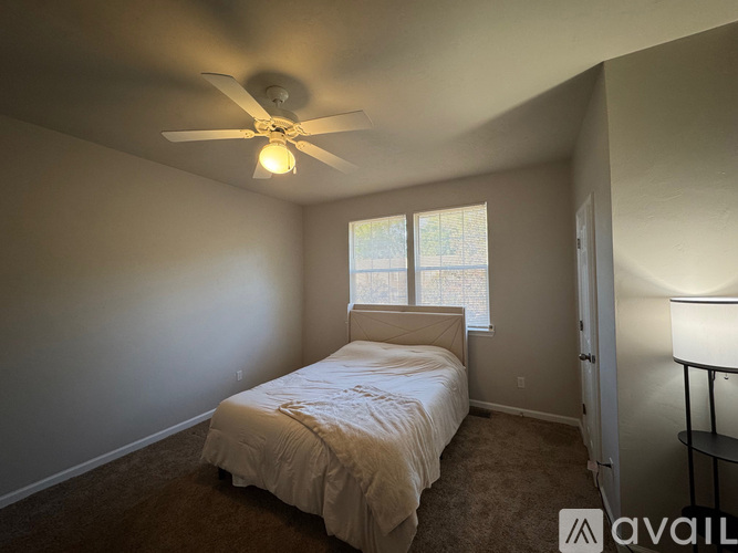 A bedroom with a bed, a ceiling fan, and a window.