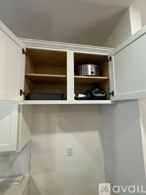 A kitchen cabinet with a pot on the top shelf.