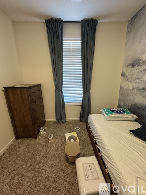 A bedroom with a bed, a wooden dresser, and a window with curtains.