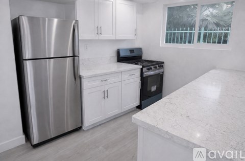 A kitchen with a refrigerator, stove, and cabinets.