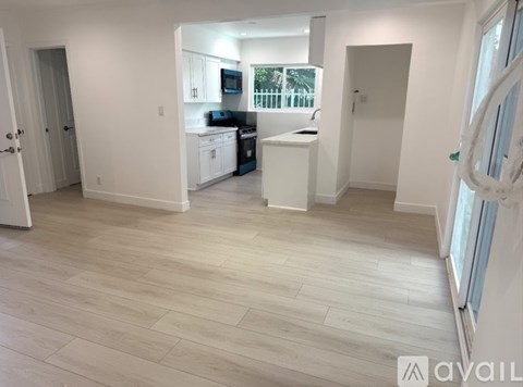 A kitchen with white cabinets and a wooden floor.