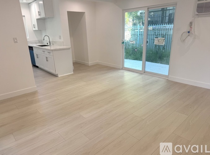 A kitchen with white cabinets and a wooden floor.