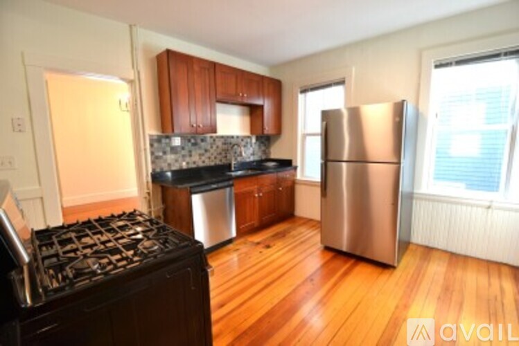 A kitchen with wooden floors and a stainless steel refrigerator.