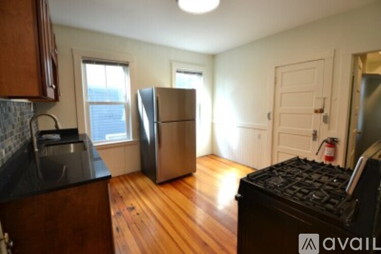 A kitchen with a black counter top and a stainless steel refrigerator.