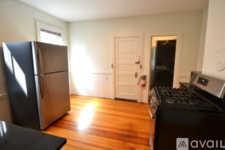 A kitchen with a black fridge and wooden floors.