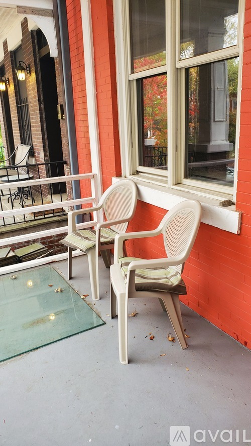 Two white chairs are placed on a glass table outside a building.