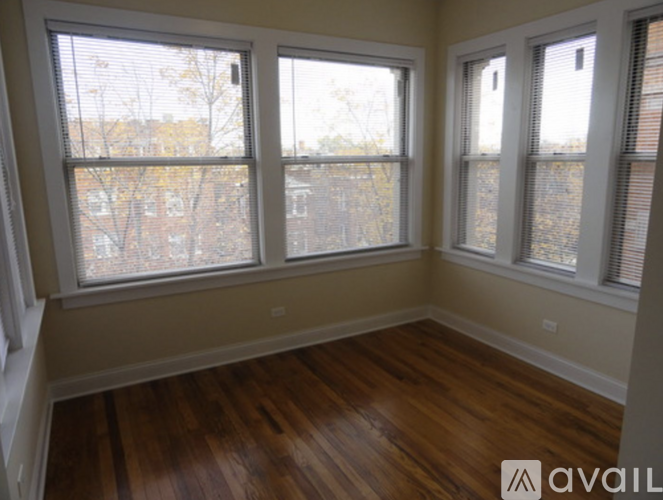 A room with wooden floors and three windows.