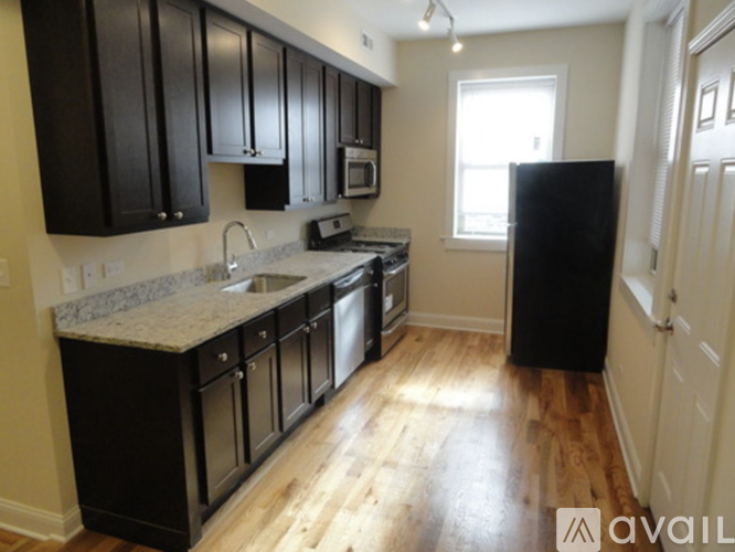 A kitchen with black cabinets and a granite countertop.