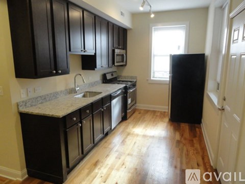 A kitchen with black cabinets and a granite countertop.