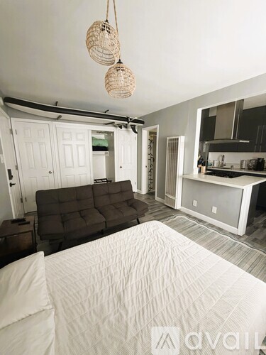 A bedroom with a bed, couch, and kitchen area.
