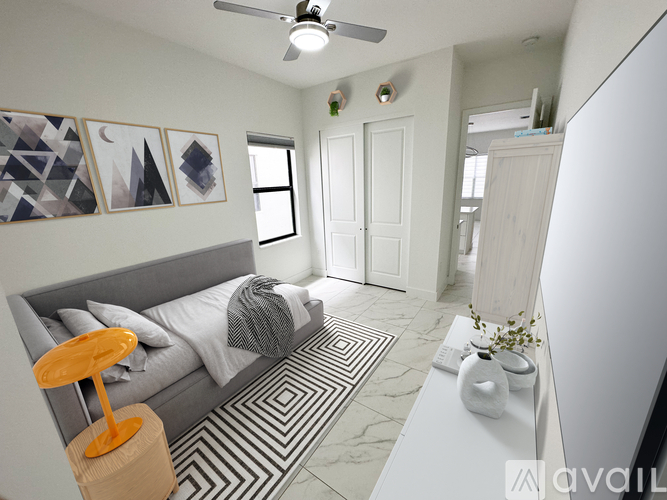 A bedroom with a grey bed and a ceiling fan.