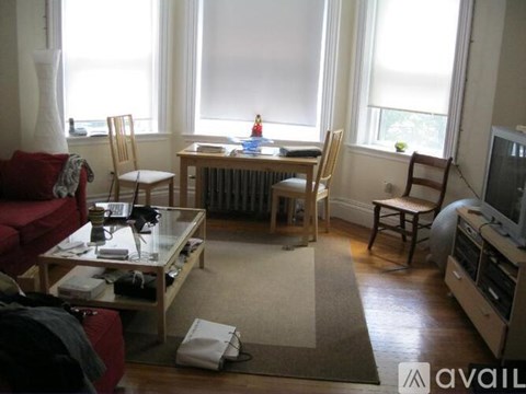 A living room with a red couch, a glass table, and a television.