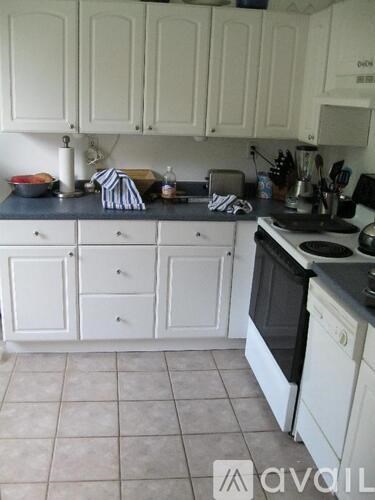 A kitchen with white cabinets and black countertops.