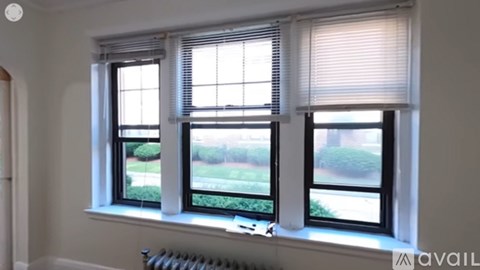 Three windows with blinds and a view of a green lawn outside.