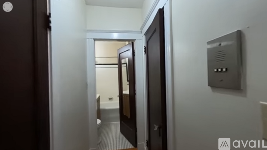 A hallway with a door on the left and a wall-mounted thermostat on the right.
