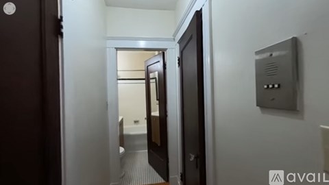 A hallway with a door on the left and a wall-mounted thermostat on the right.