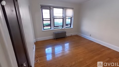 A room with wooden floors and a window with a view of the outside.