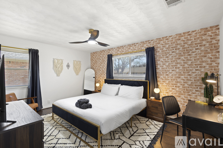 A bedroom with a brick wall and a bed with a black headboard.