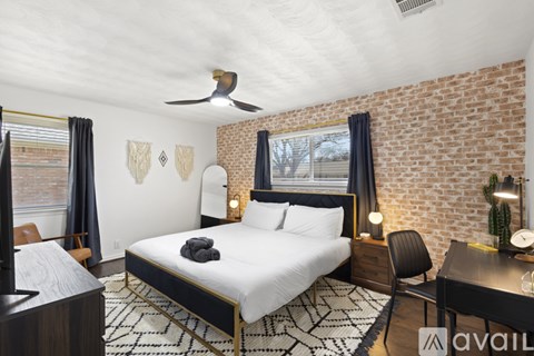 A bedroom with a brick wall and a bed with a black headboard.
