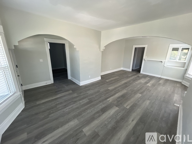 A spacious room with grey flooring and arched doorways.