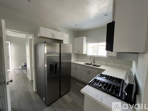 A kitchen with a stainless steel refrigerator and a white stove top.