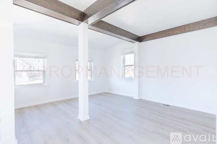 A spacious room with wooden beams and white walls is available for rent.