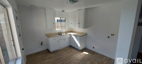 A kitchen with white cabinets and a wooden floor.