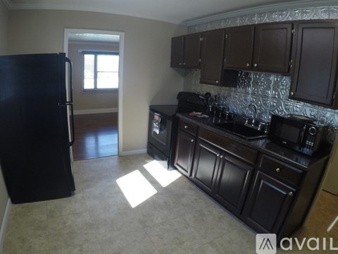 A kitchen with black cabinets and a black fridge.