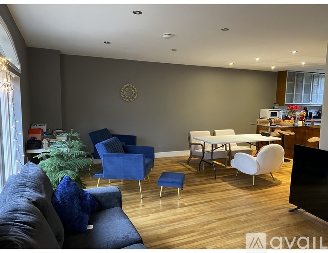 A living room with a blue couch and white chairs.