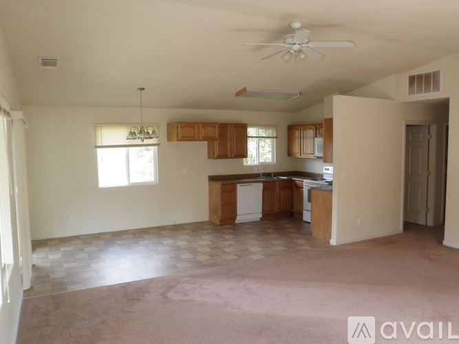 A spacious living room with a kitchen area in the background.