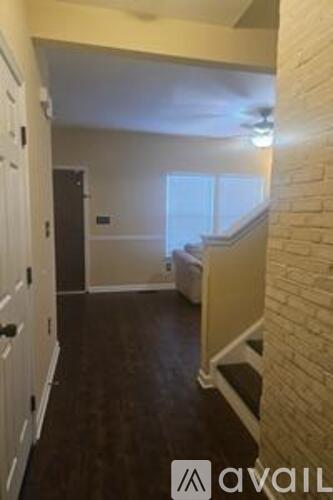 A hallway with a brick wall and a staircase.