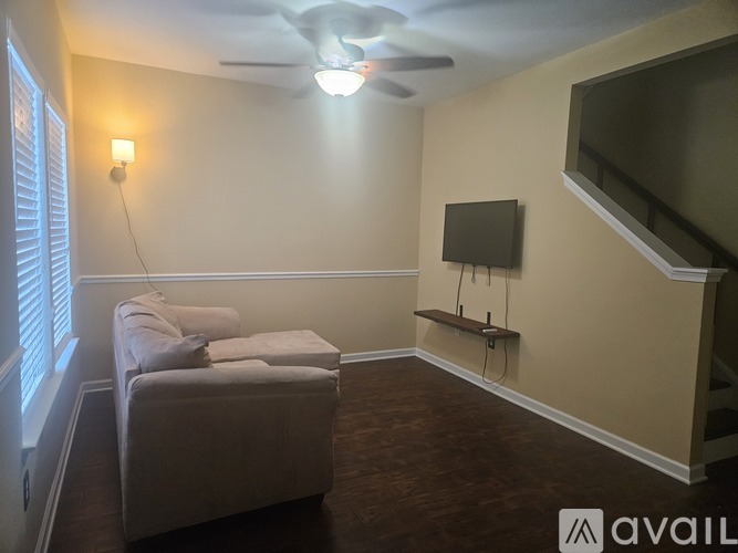 A living room with a couch, television, and stairs.