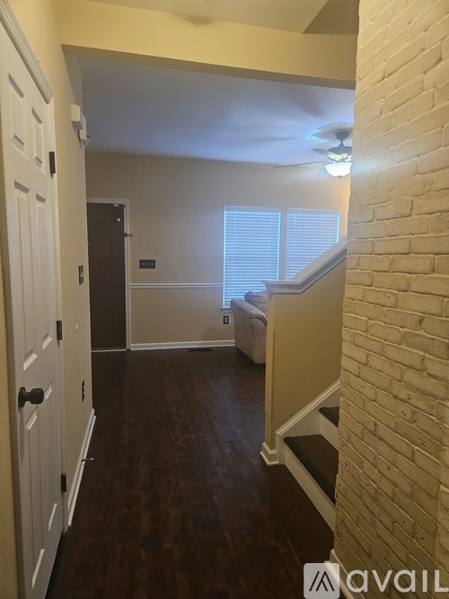 A hallway with a white door and a brick wall.